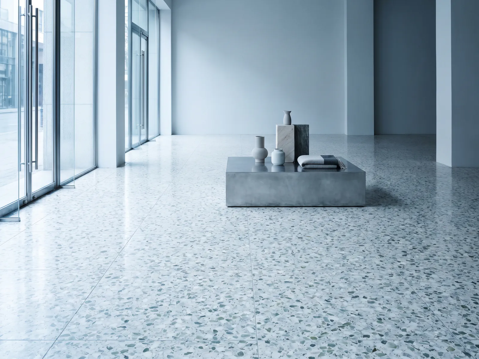 Vast honed terrazzo floor in an empty retail lobby with glass front