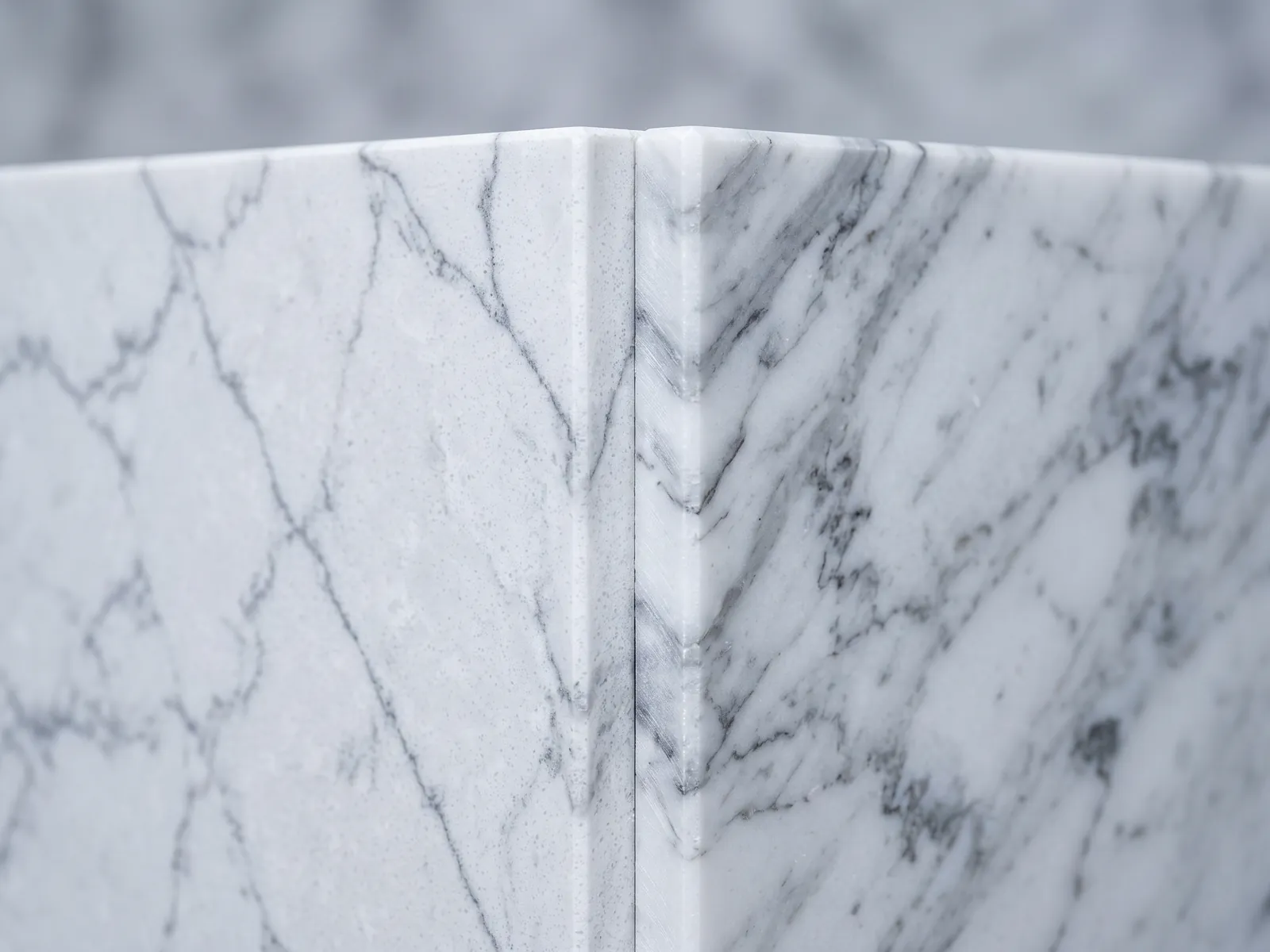 Edges of engineered and natural marble slabs meeting under studio light