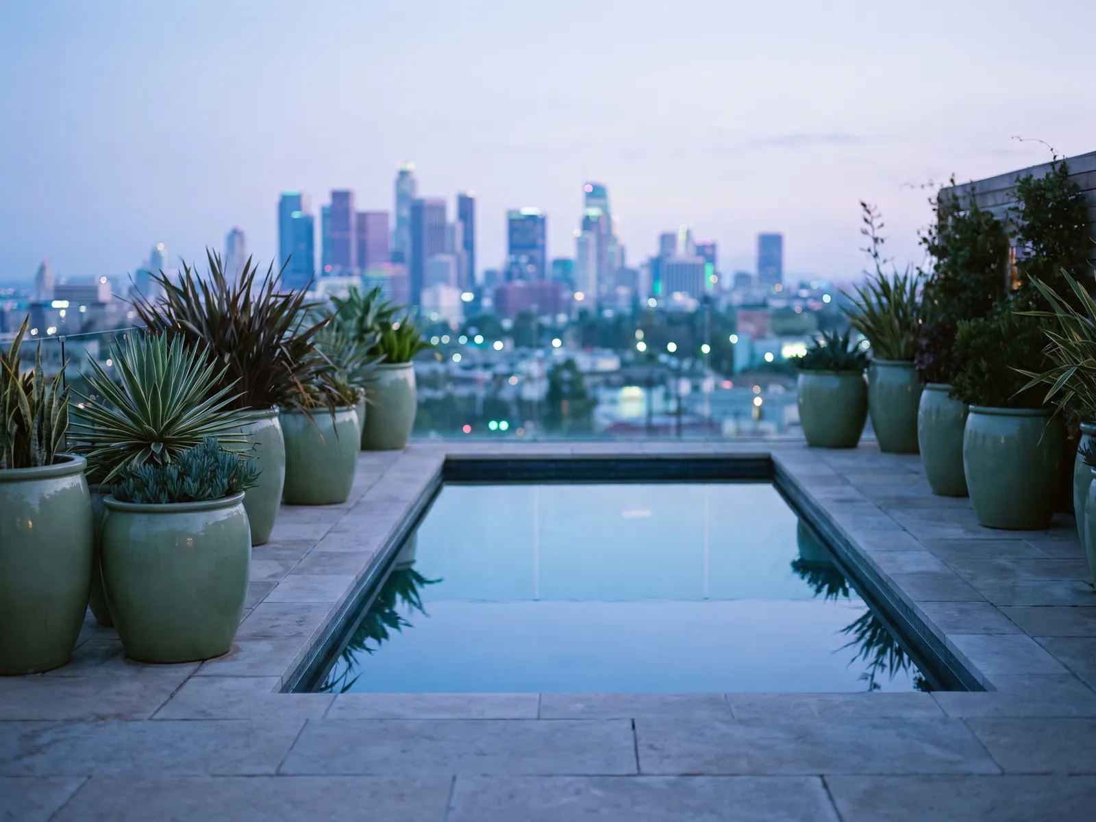 Rooftop terrace spa pool at dusk with stone deck and sage planters