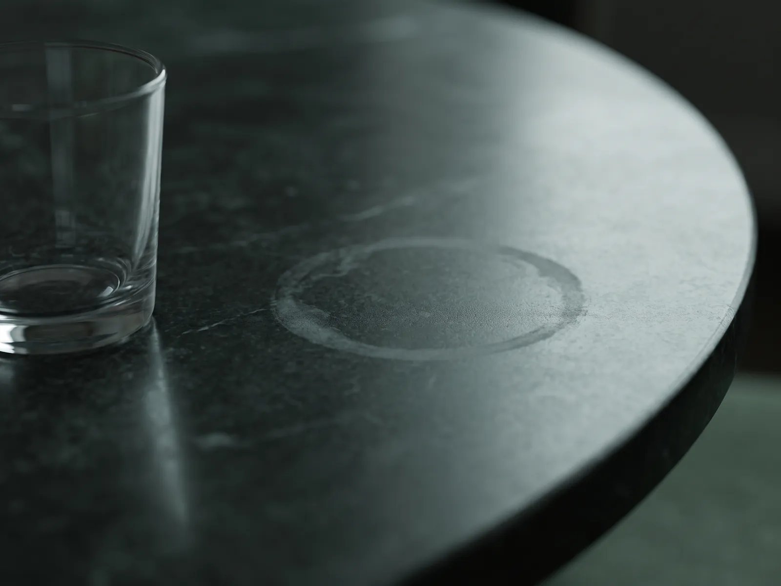 Dull etched glass ring on a dark polished marble tabletop