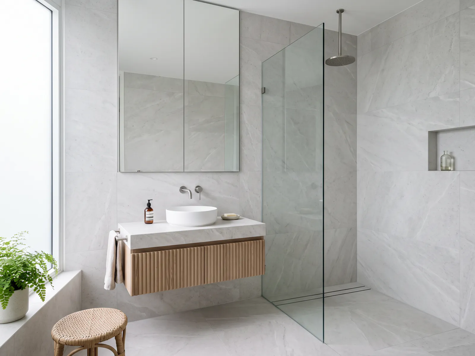 Compact washroom wrapped in one pale stone with frameless glass