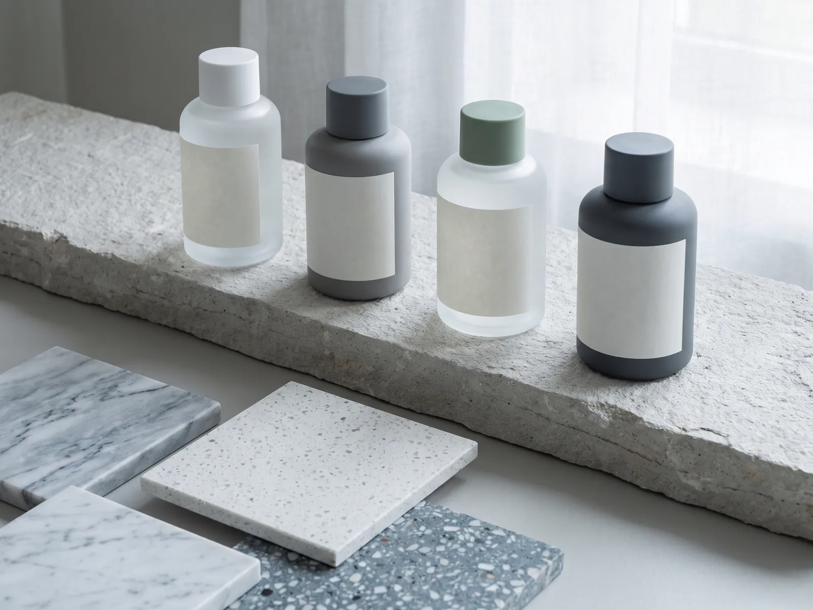 Four care bottles on a stone shelf above marble, quartz and terrazzo tiles