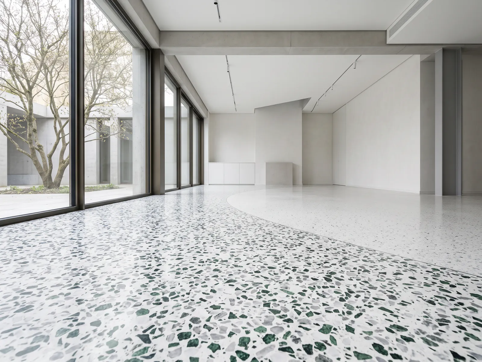 Terrazzo floor with green and grey marble chips sweeping through a sunlit room