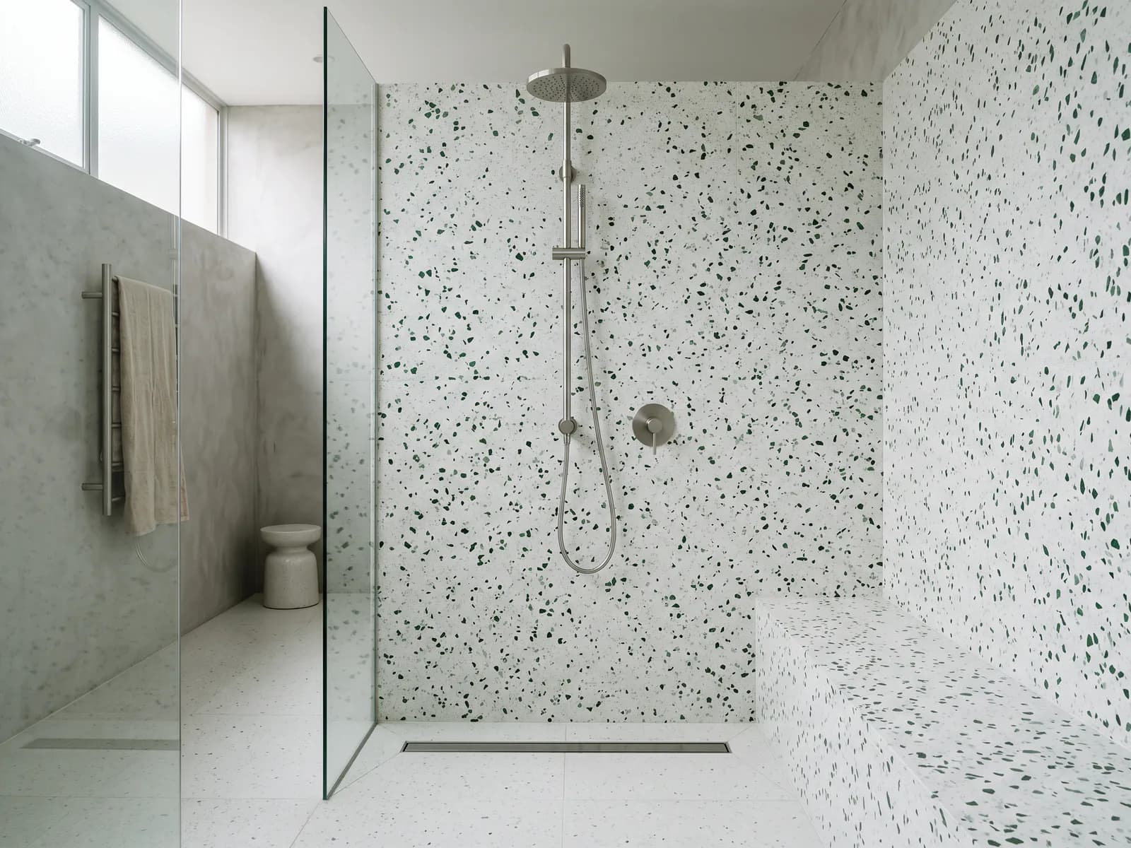 Full-height terrazzo shower walls with a brushed metal shower column