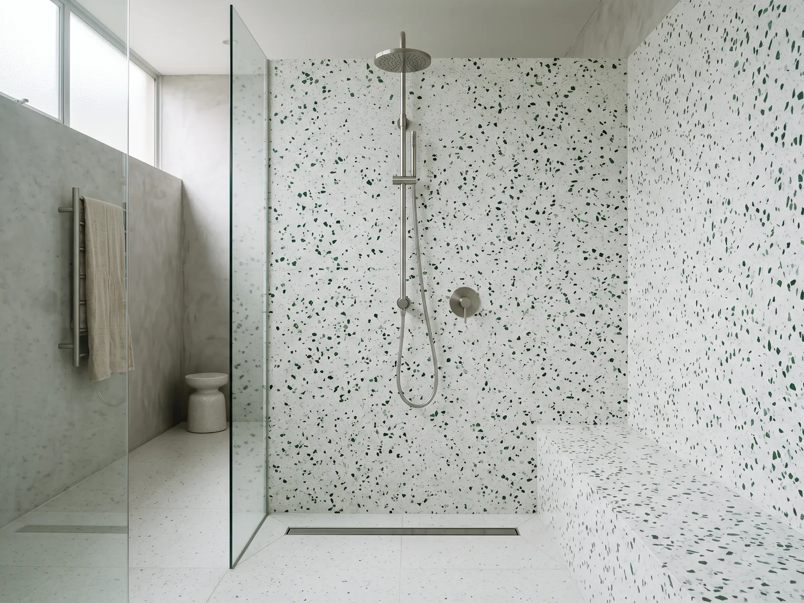 Full-height terrazzo shower walls with a brushed metal shower column