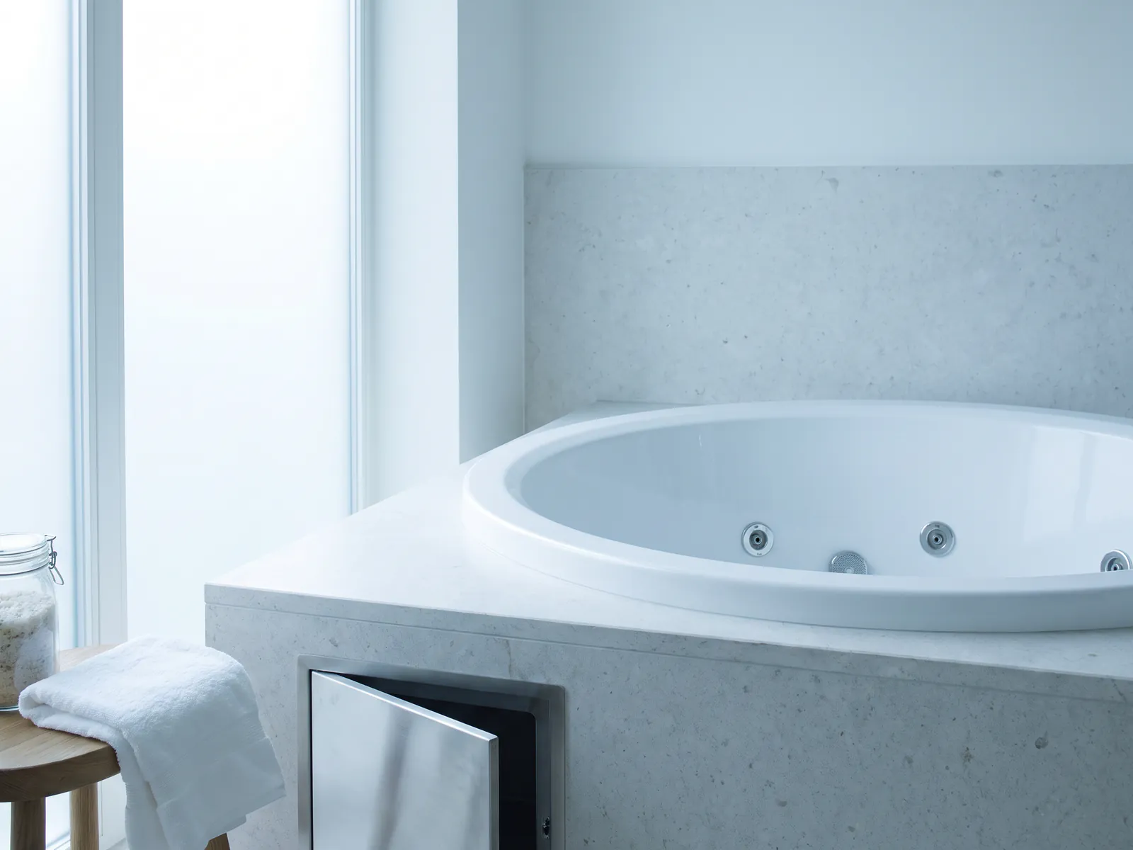 White whirlpool bath in a stone surround with access panel detail