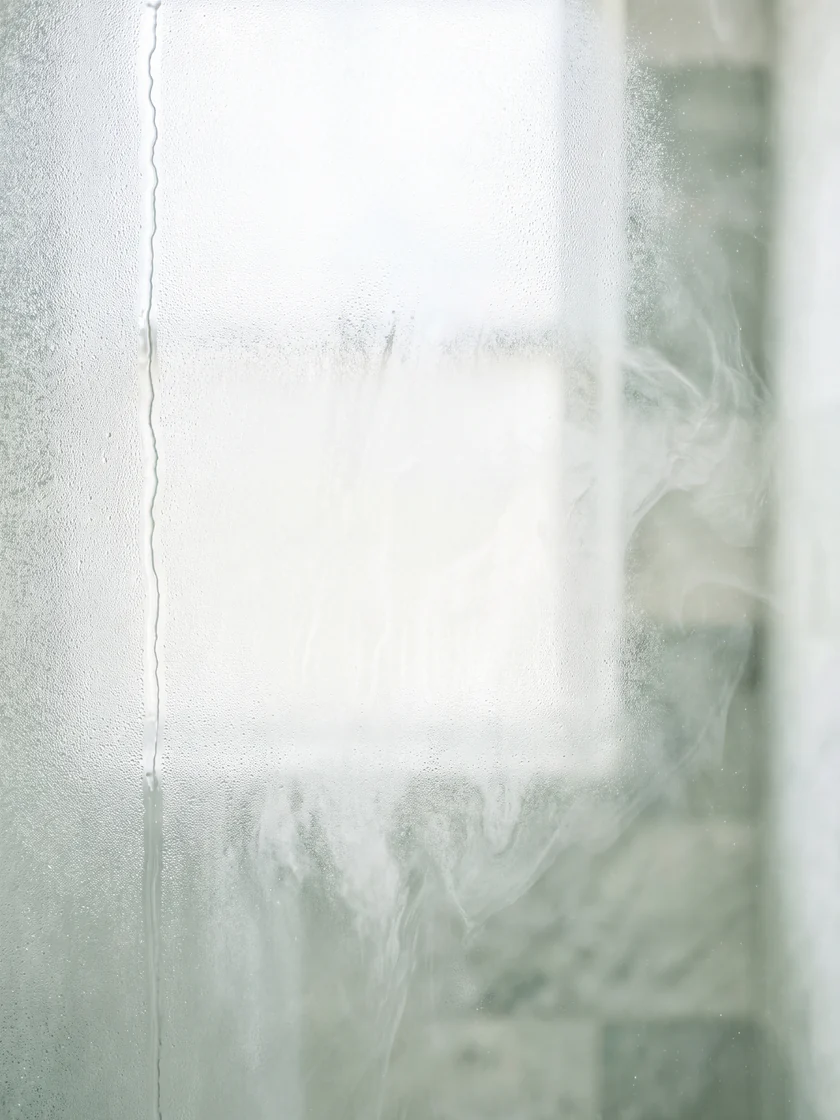 Condensation on pale glass in front of a sage stone interior